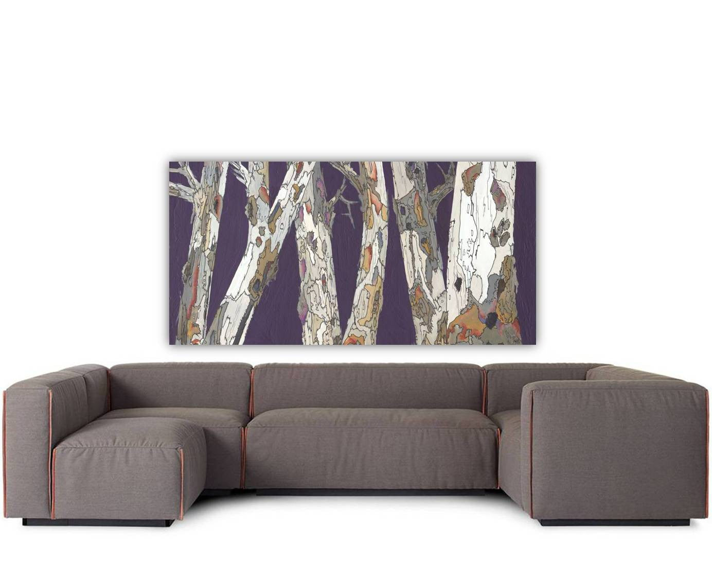 Oversized horizontal wall art canvas print of trees in a landscape over a very large sectional sofa in a contemporary living room
