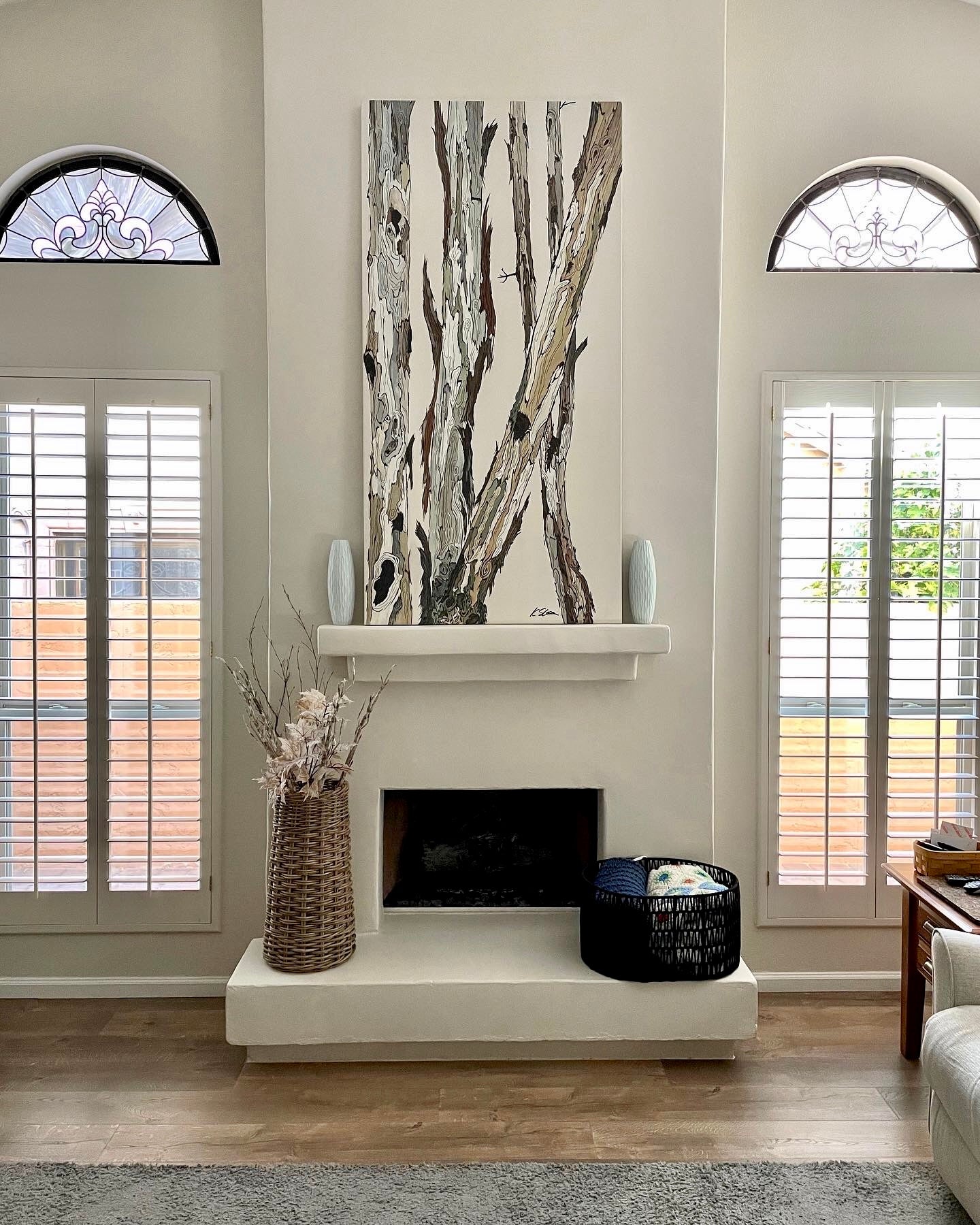 Extra long vertical canvas art of tree landscape above a modern rustic fireplace in neutral living room